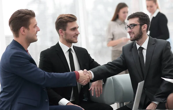 Socios concluyendo trato y estrechando la mano en presencia de los miembros del equipo — Foto de Stock