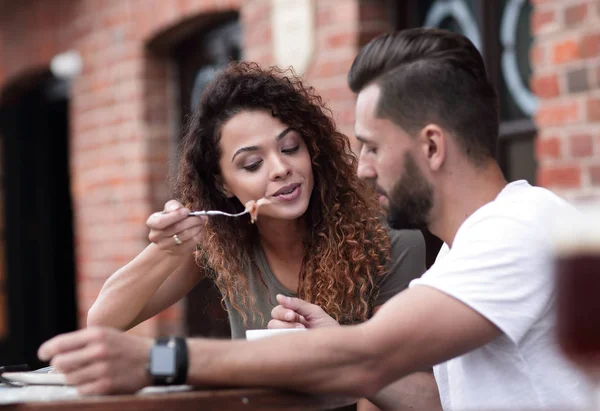 Jovem casal desfrutando de café em um café de rua e rindo — Fotografia de Stock