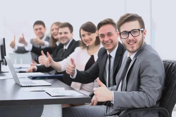 Бізнес-команда з великими пальцями вгору, сидячи на своєму столі — стокове фото