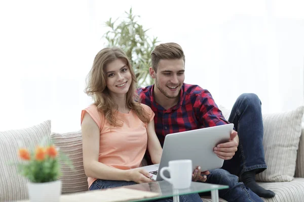 Pareja joven .working en el ordenador portátil sentado en el sofá — Foto de Stock