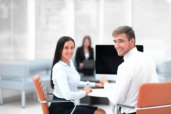 Medlemmar i affärsteamet sitter vid skrivbordet och tittar på kameran . — Stockfoto