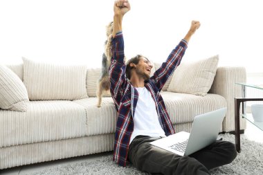 Mutlu adam oturma odasındaki kanepenin yanında köpeğiyle seviniyor..