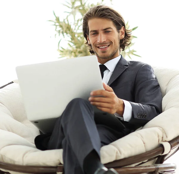 Успішний бізнесмен з ноутбуком, що сидить у великому зручному панчіші — стокове фото