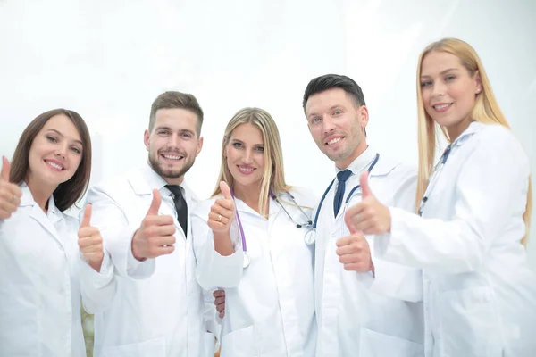 Portrét lékaře a lékařský tým ukazuje palec — Stock fotografie