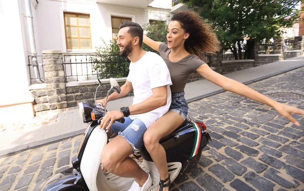 Stylish young couple sits a scooter in the street. — Stock Photo, Image