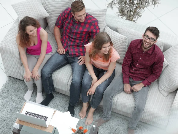 Grupo triunfante de amigos rindo enquanto sentado no sofá na sala de estar — Fotografia de Stock