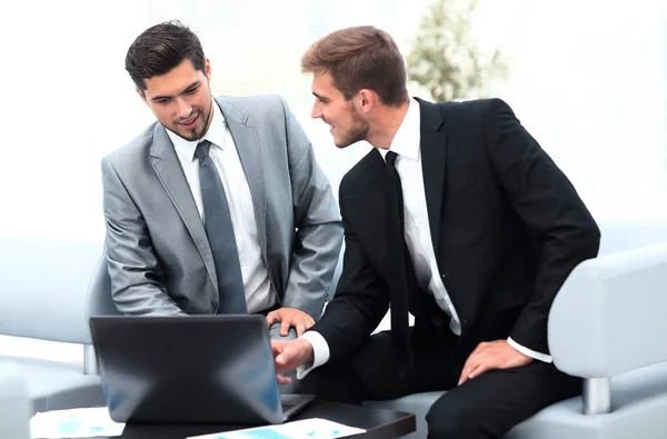 Dois colegas trabalhando em um laptop sentado no lobby do escritório . — Fotografia de Stock