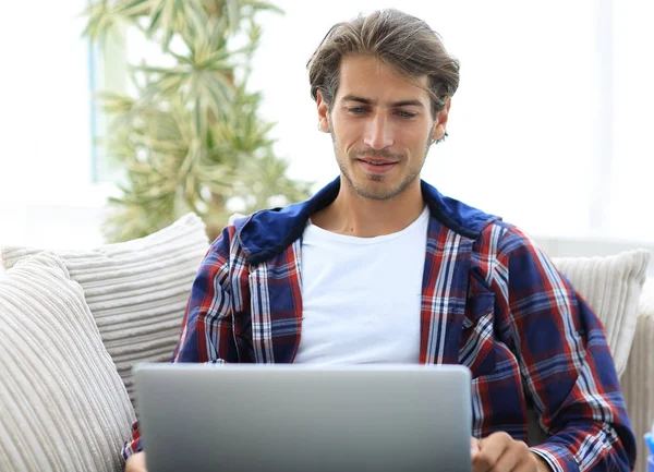 Gelukkig succesvolle jonge man kijkend naar laptop thuis. — Stockfoto