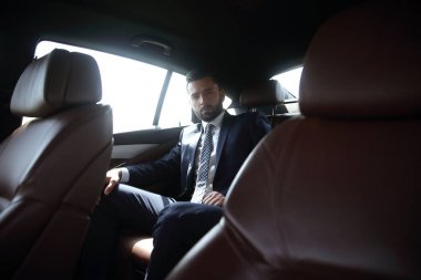 bir arabanın arka koltuğunda oturan işadamı
