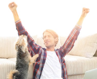 mutlu genç adam köpeğiyle oturma odasında exults