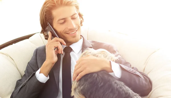 Homme d'affaires tient son animal de compagnie et parle sur un smartphone — Photo