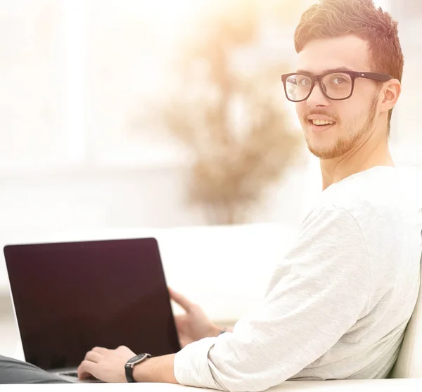 Giovane uomo moderno che lavora sul computer portatile seduto in soggiorno . — Foto Stock