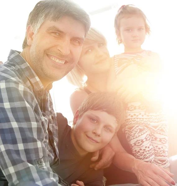 Family with two children sitting together and looking at camera — Stock Photo, Image