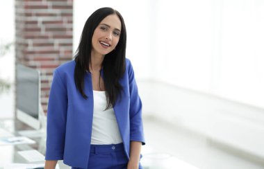 Ofiste masanın yanında duran çekici genç bir iş kadını.