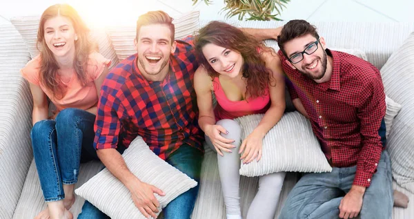 Veselá skupina přátel se směje, sedí na gauči. — Stock fotografie