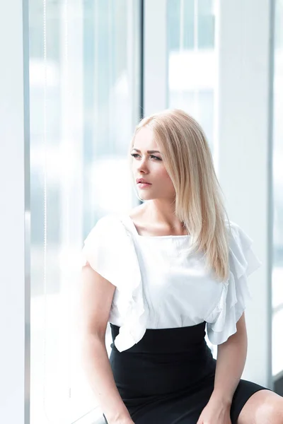 Moderne Geschäftsfrau sitzt am Fenster im Büro. — Stockfoto