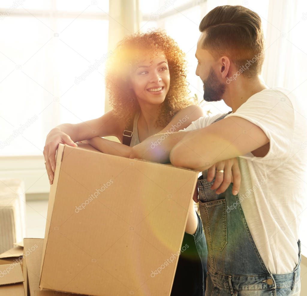 Happy couple standing near boxes in their new apartment.