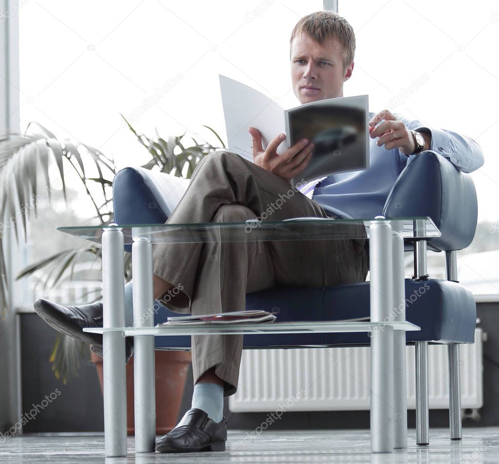Businessman reading magazine in waiting room