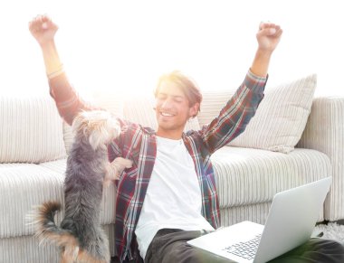 mutlu genç adam köpeğiyle oturma odasında exults