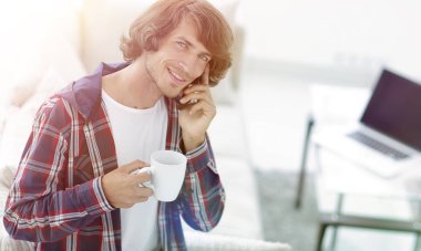 güzel bir fincan adamla bir dizüstü bilgisayar önünde oturur.