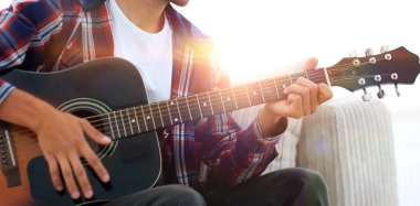 Yakışıklı adam evde kanepede gitar çalmaya