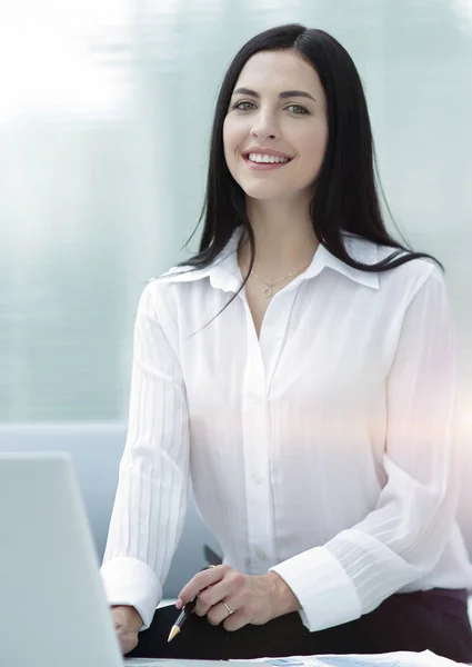 Successful young woman sitting at a desk on a blurred background — Stock Photo, Image