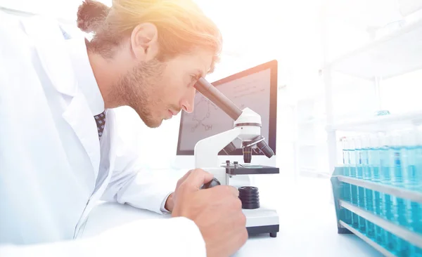 Young laboratory scientist looking at microscope in laboratory — Stock Photo, Image