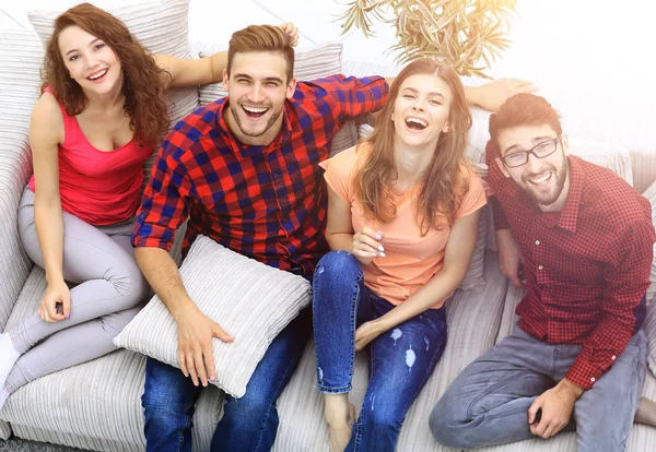 Cuatro amigos felices riendo mientras están sentados en el sofá —  Fotos de Stock