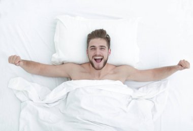 Üstten Görünüm. mutlu adam rahat bir yatakta uyanma