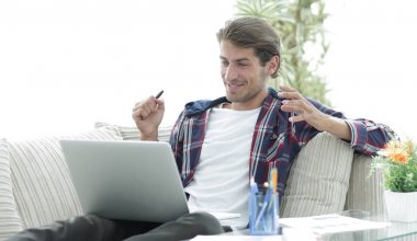 mutlu genç adam evden dizüstü bilgisayar ile çalışma.