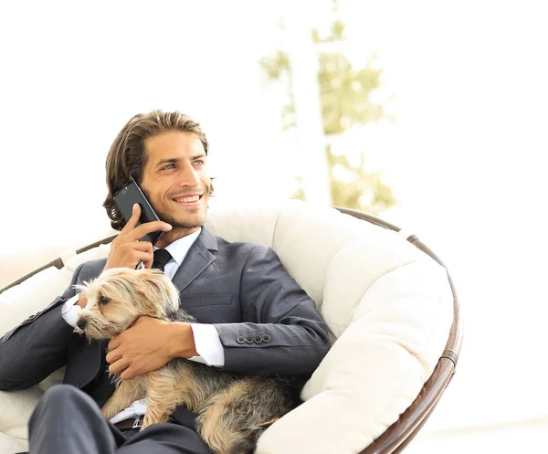 सफल व्यापारी अपना कुत्ता और पालतू जानवर रखता है और स्मार्टफ़ोन पर बात करता है — स्टॉक फ़ोटो, इमेज