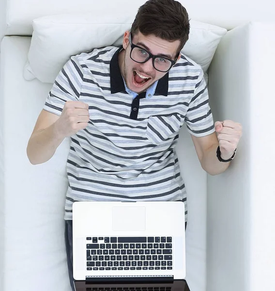 Lycklig moderna man ser på den bärbara datorn sitter i soffan. — Stockfoto