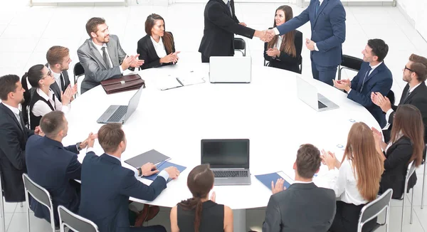 Geschäftspartner geben sich bei den Gesprächen am runden Tisch die Hand — Stockfoto