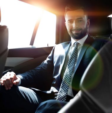 Bir arabanın arka koltuğunda oturan başarılı iş adamı