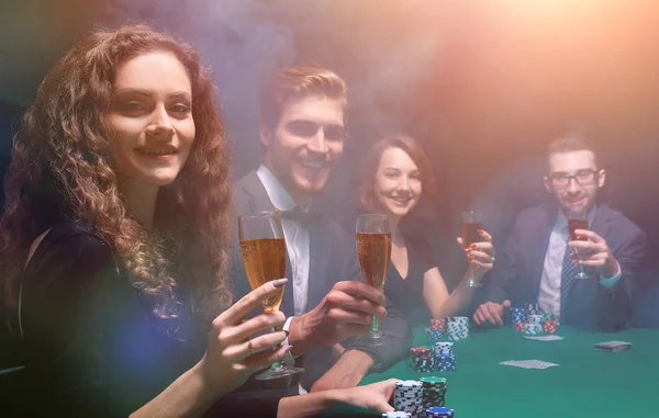 Grupo de amigos sentados à mesa de jogo no casino — Fotografia de Stock