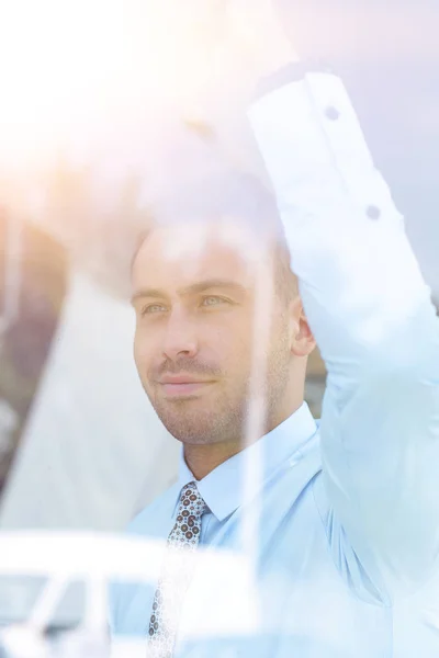 Vue de derrière glass.confident homme d'affaires regardant par la fenêtre de son bureau — Photo