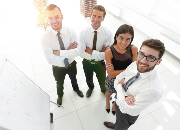 Equipo de negocios de pie junto a un rotafolio en blanco — Foto de Stock