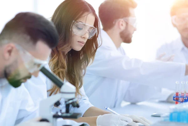Wetenschapper op zoek in een Microscoop zit in het lab. — Stockfoto