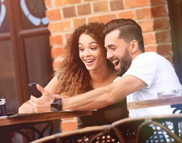 Underbara unga par tittar på smart telefon på café — Stockfoto