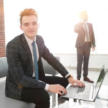 Genç işadamı ofiste dizüstü bilgisayarla çalışıyor.