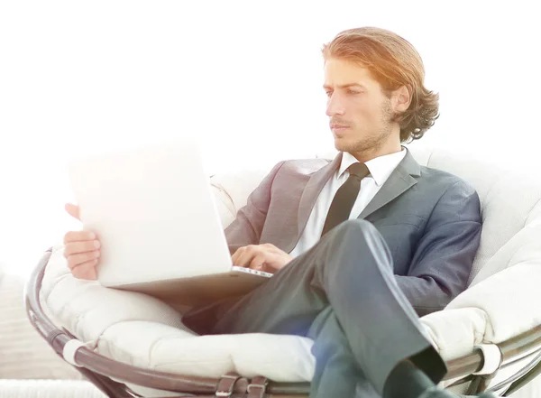 Σύγχρονο επιχειρηματία με ένα φορητό υπολογιστή που κάθεται σε μια κομψή άνετη καρέκλα — Φωτογραφία Αρχείου