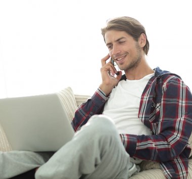 cep telefonu üzerinde konuşurken laptop ile ciddi genç adam