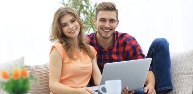Genç çift çalisarak koltukta oturan laptop