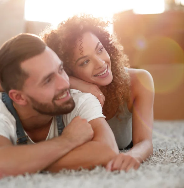 Happy couple lying on the carpet on the blurred background — Stock Photo, Image