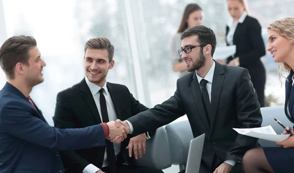 Partner che concludono un accordo e stringono la mano alla presenza dei membri del team — Foto Stock