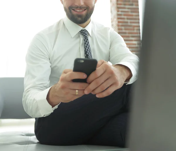 Empresário segurando um smartphone e olhando para a câmera — Fotografia de Stock