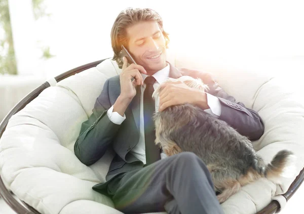 Businessman is holding his pet and talking on a smartphone — Stock Photo, Image
