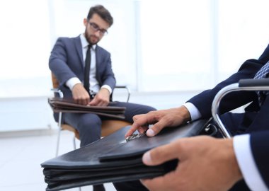 Klasik elbiseli adam kahverengi çanta yakın tutar