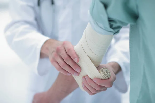 Medico che applica una benda elastica sul gomito del paziente . — Foto Stock