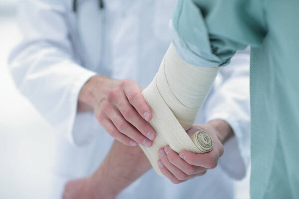 doctor applying elastic bandage on the elbow of the patient.